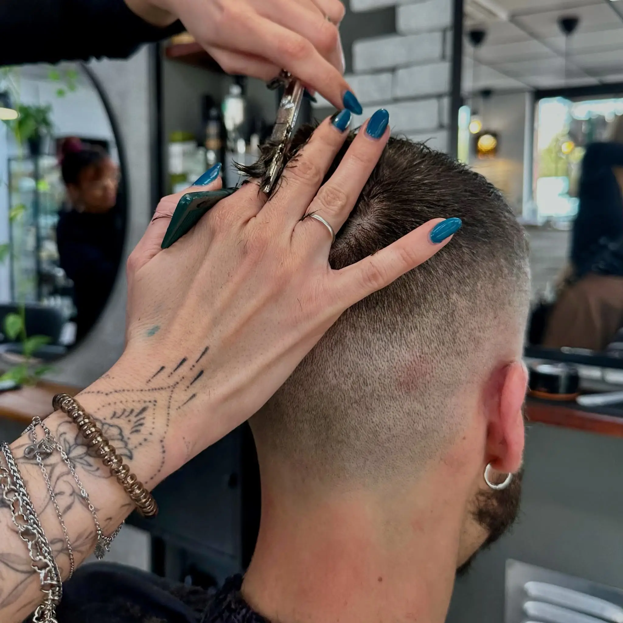 Hombre con corte de pelo moderno siendo atendido por un barbero profesional en la barbería