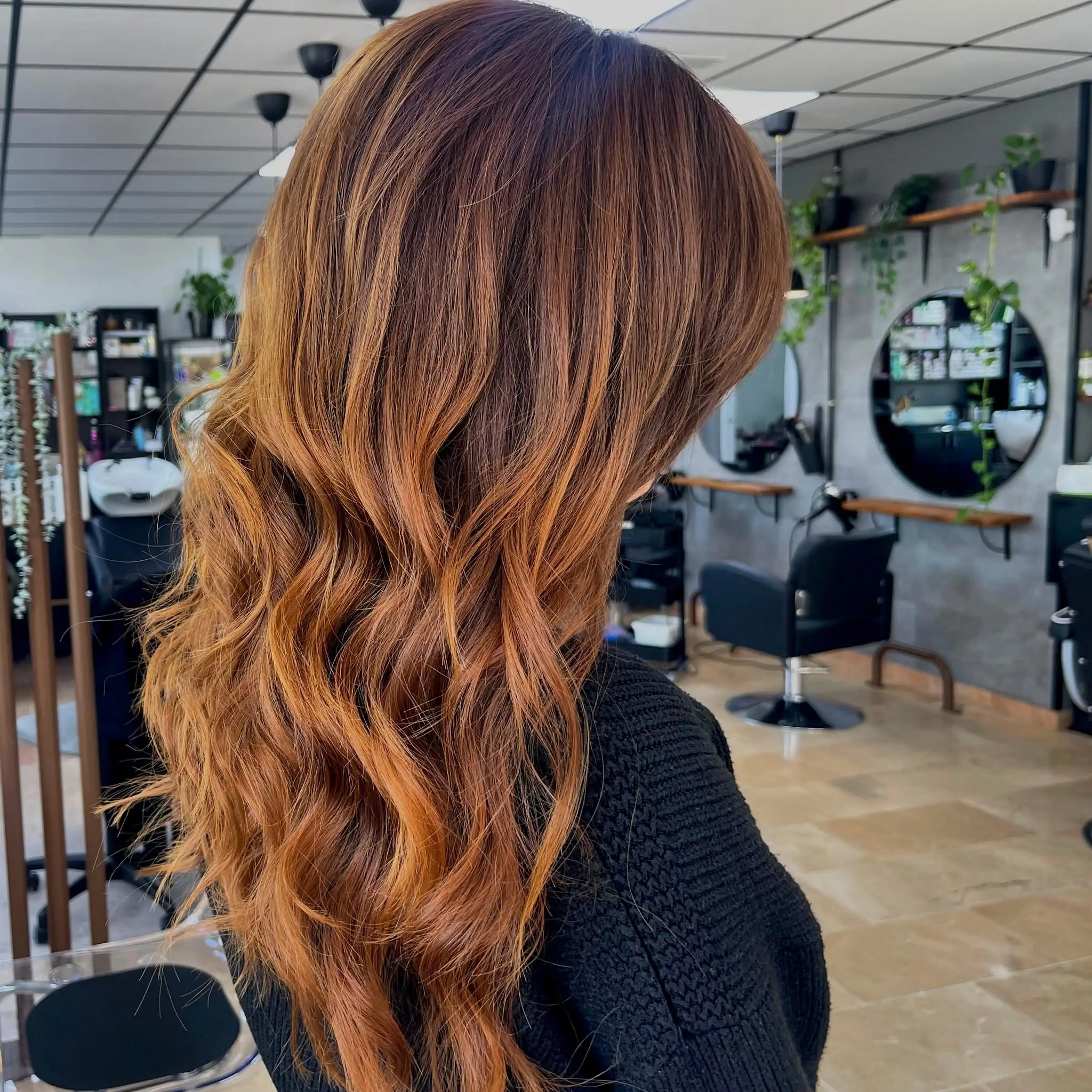 Mujer con coloración cobriza rose gold recibiendo un tratamiento capilar en el salón de belleza